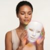 Woman looking at LED facial mask held with both hands