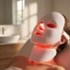 Relaxed woman using LED facial mask with red light therapy