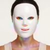 Front view of woman wearing LED facial mask with rainbow light
