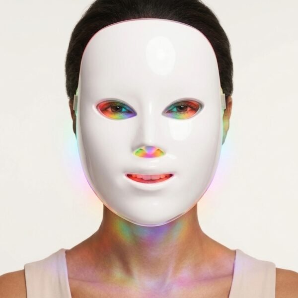 Front view of woman wearing LED facial mask with rainbow light